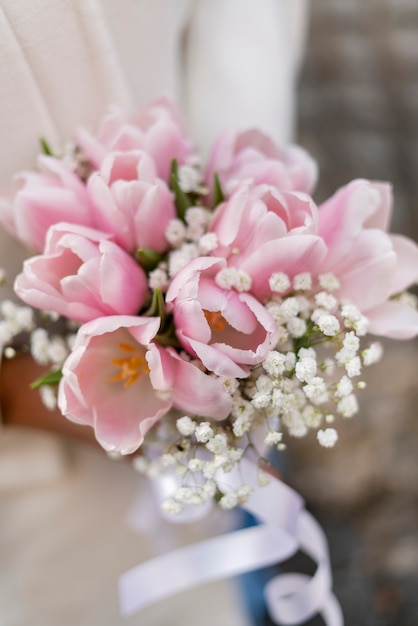 Close-up of a beautiful wedding bouquet of pink white tulips in the hands of the bride. High quality photo