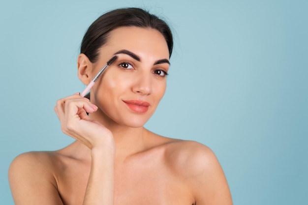 Close up beauty portrait of a woman with perfect skin and natural makeup, full nude lips, holding an eyebrow brush