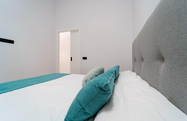 Close up of a bed in a master bedroom in white with a double bed, air conditioning and a wardrobe on