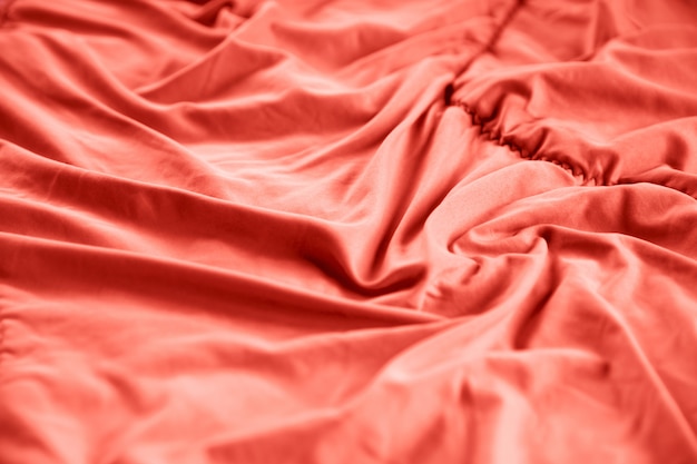 Close up of bedding sheets with coral color on morning bed.