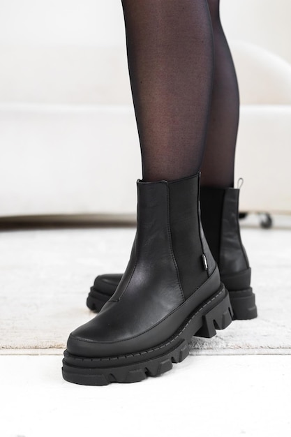 Close-up black elegant shoes on women's legs. Leather winter boots, stylish lady footwear concept photo