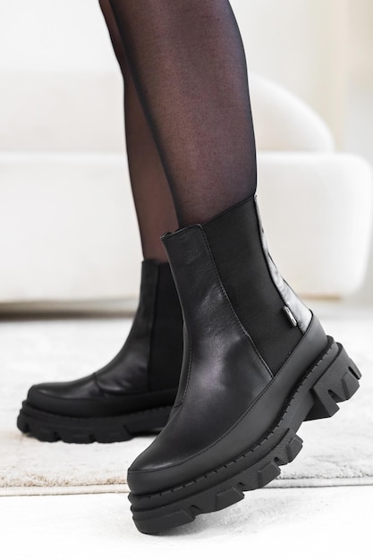 Close-up black elegant shoes on women's legs. Leather winter boots, stylish lady footwear concept photo