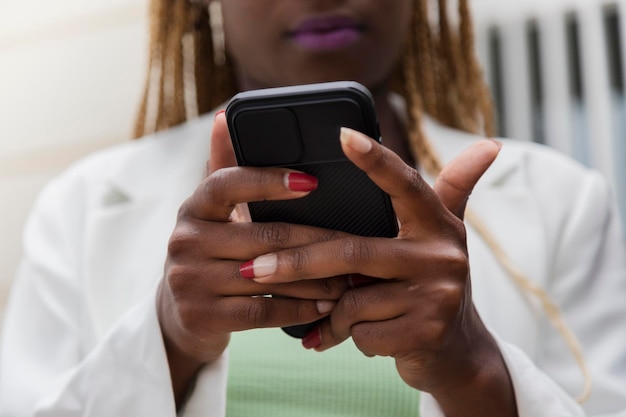 Close up of black hands holding a cellphone. Mobile phone addiction. Technology concept.