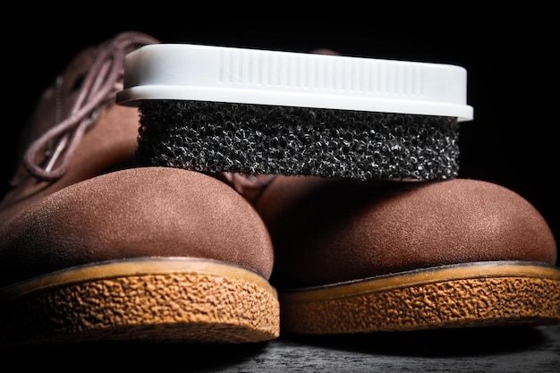 Close up of black hard foam sponge for suede shoes on brown boots