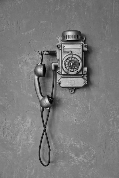 Close up black and white old vintage wired telephone for communication on gray wall Antique phone from past for design backgrounds