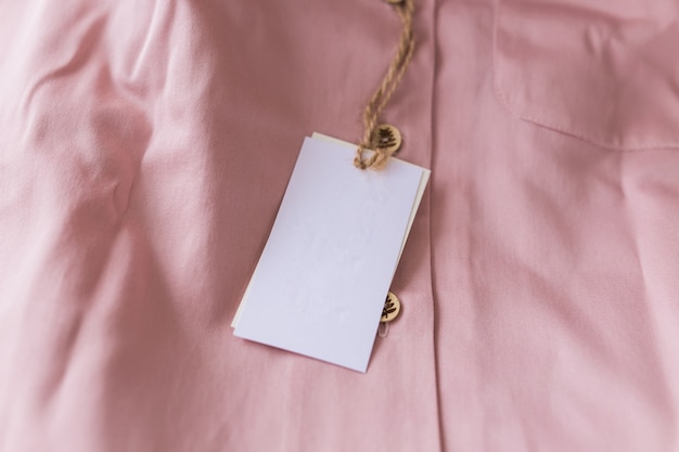 Close-up blank tag label on pink shirt. Copy space. space for advertisement.