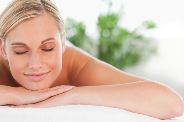 Close up of a blonde smiling woman relaxing on a lounger with eyes closed