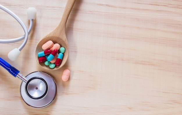 Close up blue stethoscope and pills in wood spoon