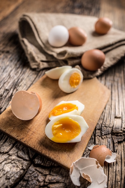 Close-up boiled or raw chicken eggs on wooden board.