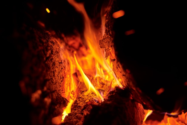 Close up of bonfire with a sparks at night. Heat from burning logs and coals in the dark