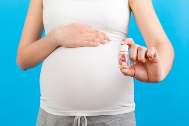 Close up of a bottle of vitamin pills in pregnant woman's hand at colorful background with copy space Healthcare concept