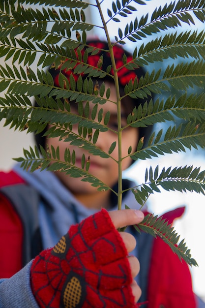 Photo close-up of boy standing by tree leaf