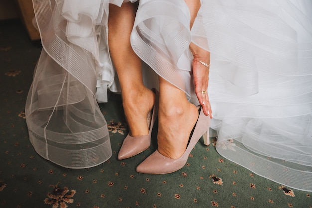 Close up of bride putting on elegant shoes and wedding dress