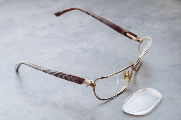 Close up of broken eyeglasses with damaged frame and lens lying on table in optical store