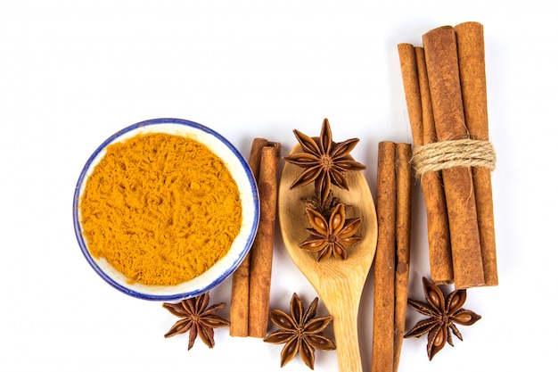 Close up the brown cinnamon stick and powder with star anise spice in wooden spoon isolated on white  