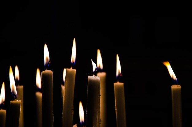 Close-up of burning candles against black background