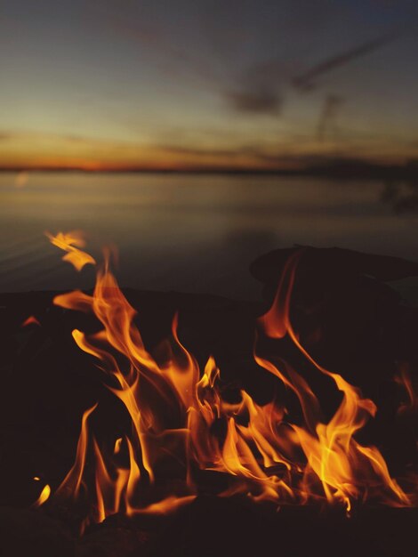 Close-up of burning flames against dark sky during sunset