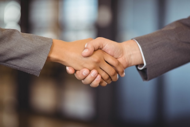 Close-up of business man shaking hands with business woman in office