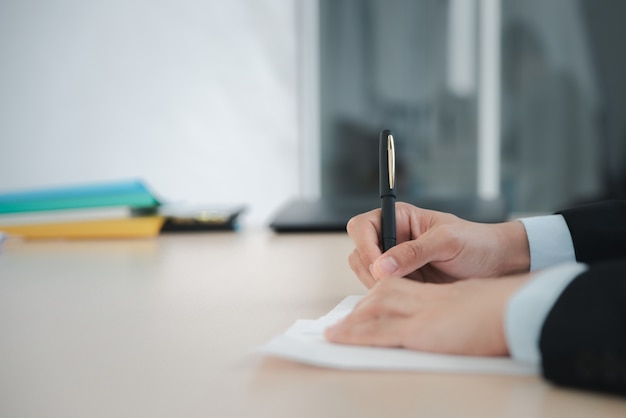 Close up business man writing or signing contract on paper in office.