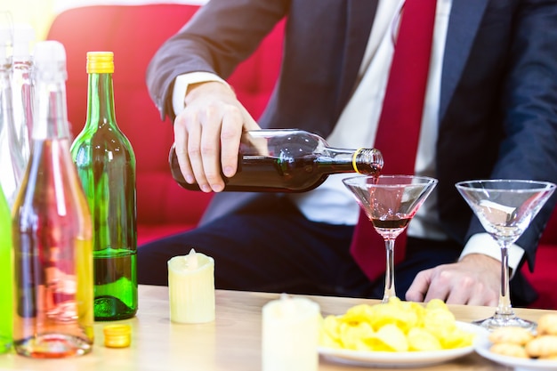 Close up of a business suit of man Pouring champagne into glass