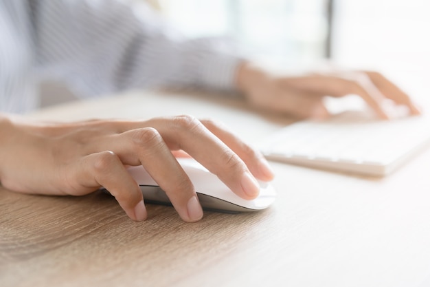 Close up of business woman hand typing on computer keyboard with the mouse while sitting