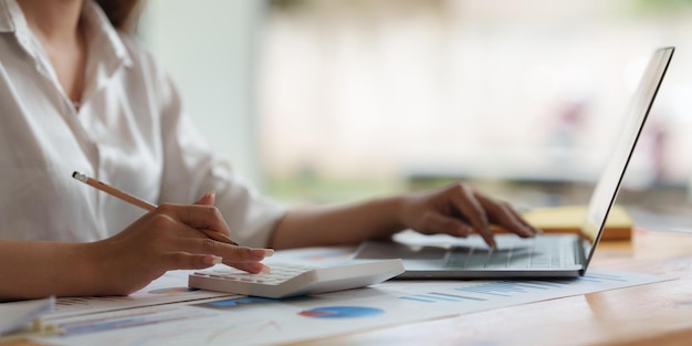 Close up Business woman hand using calculator to calculate the company's financial results and budget Account Audit Concept