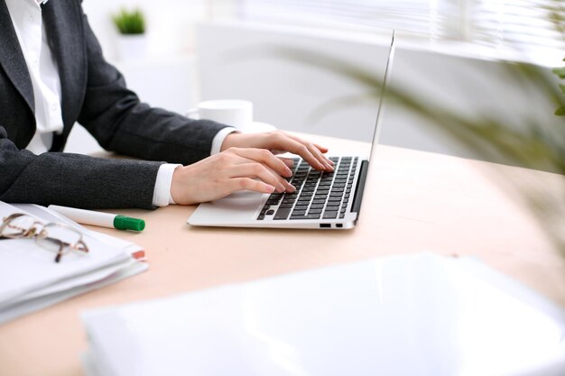 Close up of business woman  hands  typing on  laptop computer in the white colored office.