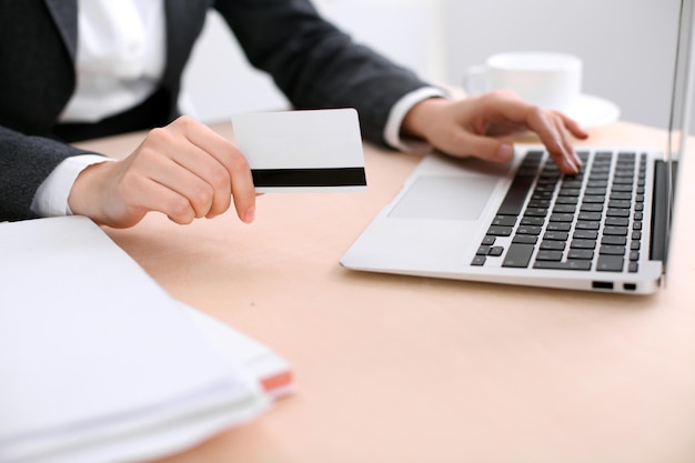 Close up of business woman hands using credit card and laptop computer