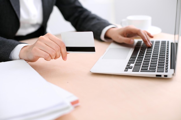 Close up of business woman hands using credit card and laptop computer.