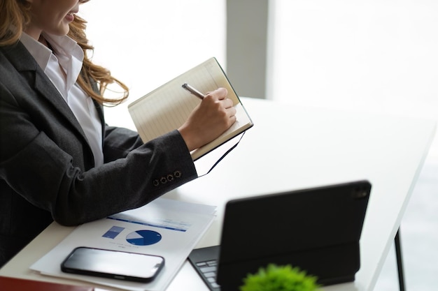 Close up business woman looking at laptop computer watching online webinar training or having virtual meeting video conference taking notes doing market research working in office