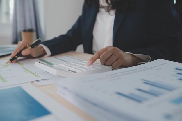 Close up Business woman using calculator and laptop for do math finance on wooden desk tax accounting statistics and analytical research concept