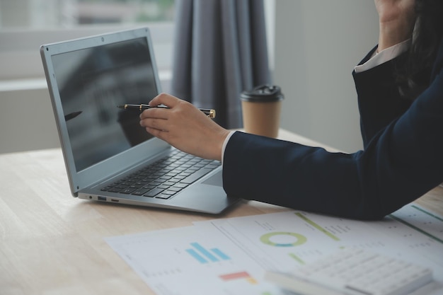 Close up Business woman using calculator and laptop for do math finance on wooden desk tax accounting statistics and analytical research concept