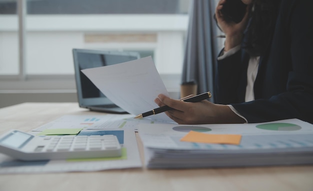 Close up Business woman using calculator and laptop for do math finance on wooden desk tax accounting statistics and analytical research concept