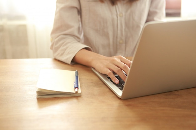 Close up business woman using laptop on wooden desk