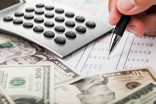 Close-up of a Businessman Analyzing Financial Figures with Calculator and Banknotes