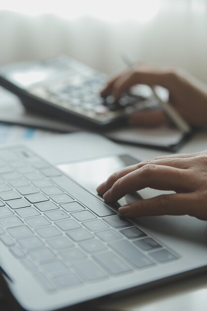 Close up businessman hand using calculator and working with laptop calculate about finance accounting at coffeeshop outdorfinance accounting concept