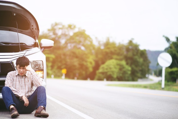 Close up businessman hand using a mobile smart phone call a car mechanic ask for help assistance because car broken roadside people journey friends sit wait beside broken car