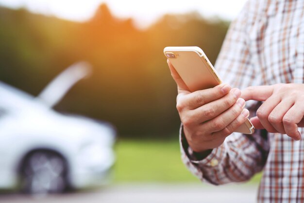 Close up businessman hand using a mobile smart phone call a car mechanic ask for help assistance because car broken roadside people journey friends standing wait beside broken car background