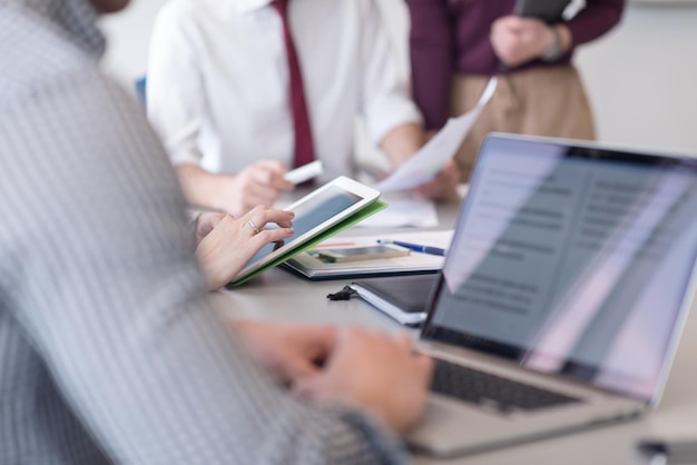 close up of  businessman hands  using tablet  people group in office meeting  room blurred in backgronud