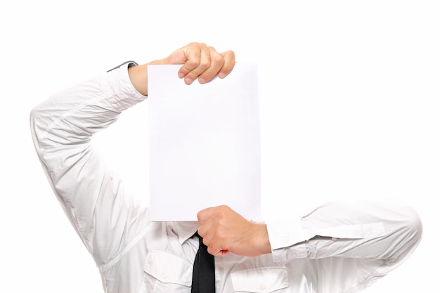 A close-up of a businessman hiding behind a sheet of white paper