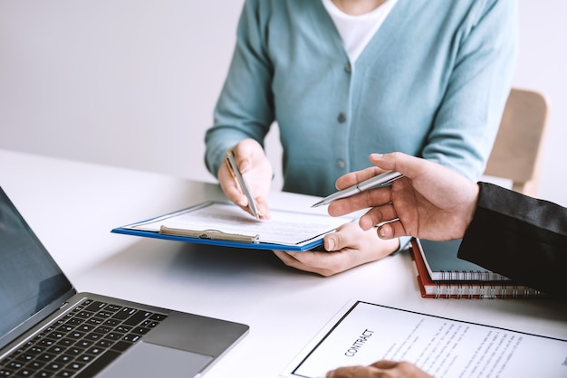 Close-up of a businessman holding a pen read the terms of signing contract documents at the office.