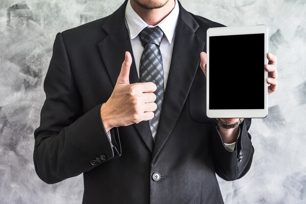 Close up of businessman holding tablet device on grunge background.