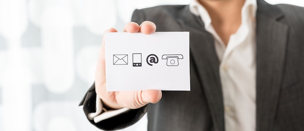 Photo close up of businessman showing a white card with contact icons  conceptual of business information center and support