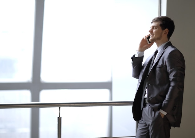 close up.businessman talking on smartphone while standing near an office window.