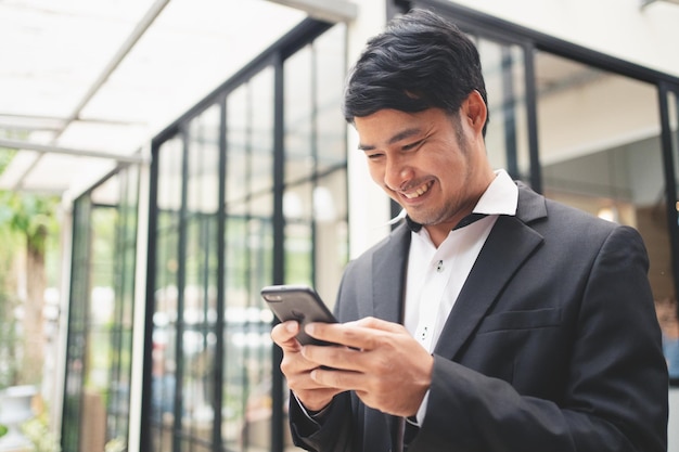 Close up businessman typing on smart phone and smilling