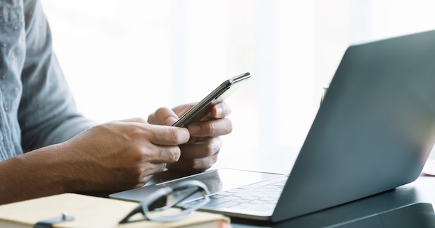 Close up businessman using smart phone at office