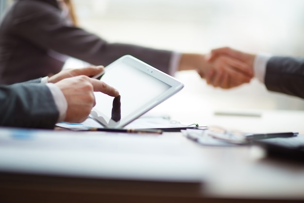 Close up. businessman with a digital tablet sitting at the meeting table .