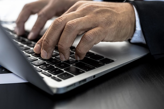 Close-up A businessman working in a private room, He is typing on a laptop keyboard, He uses a messenger to chat with a partner. Concept of using technology in communication.