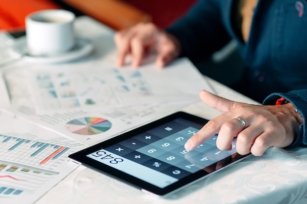 Close-up Of A Businessperson's Hand Analyzing Bill On Digital Tablet Over Desk.