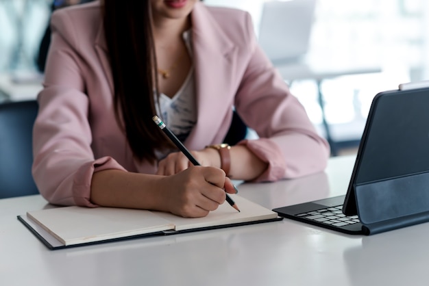 Close-up of a businesswoman hand holding a pencil while taking notes at the office.